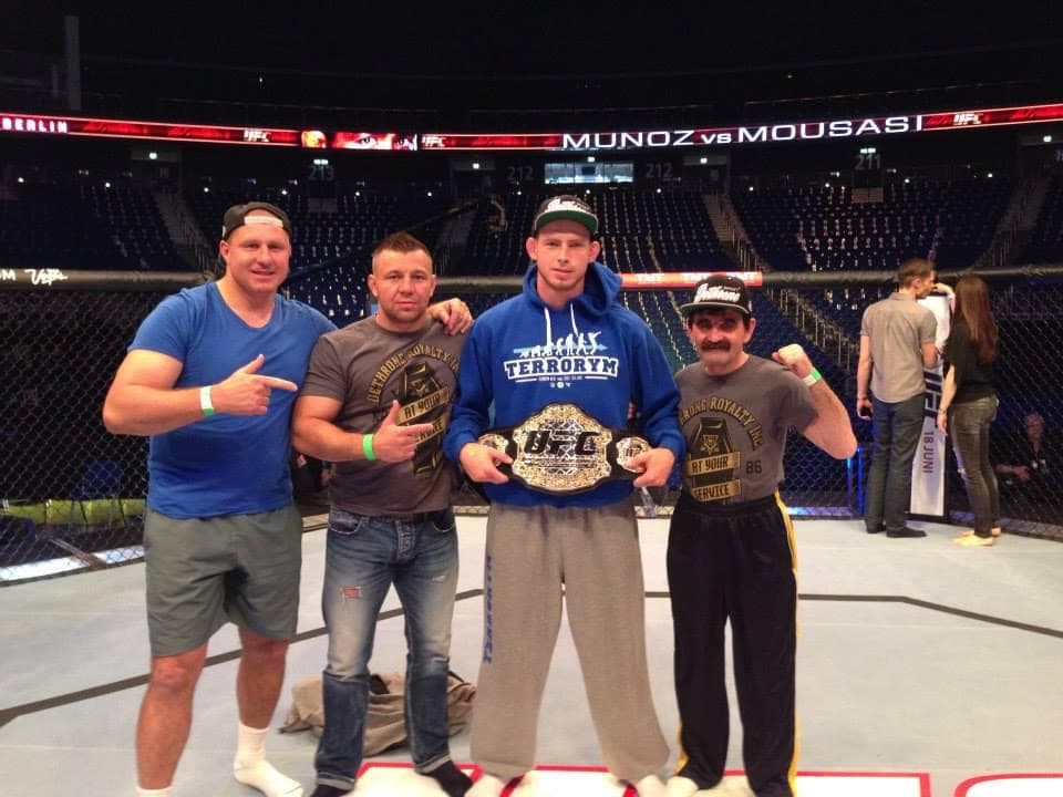 Krzysztof Jotko z pasem UFC w oktagonie, obok Mirosław Okniński i sztab