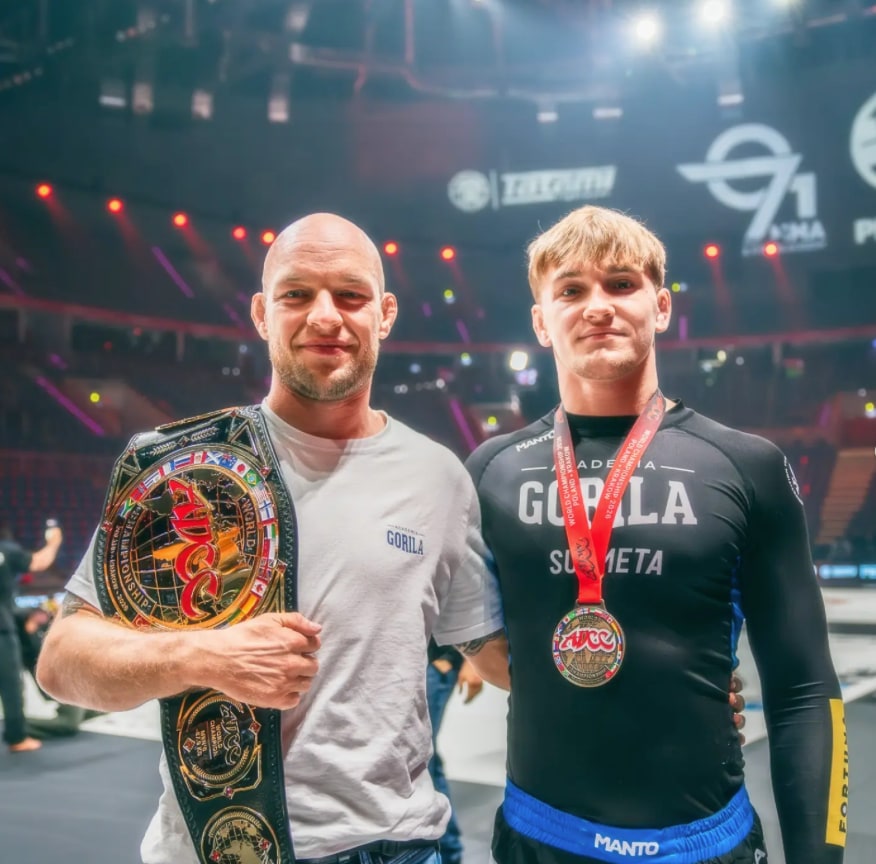 Marcin Polczyk z pasem mistrzowskim ADCC i Paweł Jaworski z medalem na szyi, w hali po zawodach